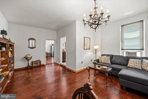 a living room with furniture a chandelier and a wooden floor