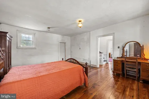 a bedroom with a bed and a dresser with wooden floor