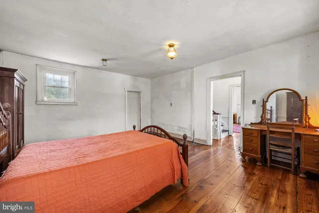 a bedroom with a bed and a dresser with wooden floor