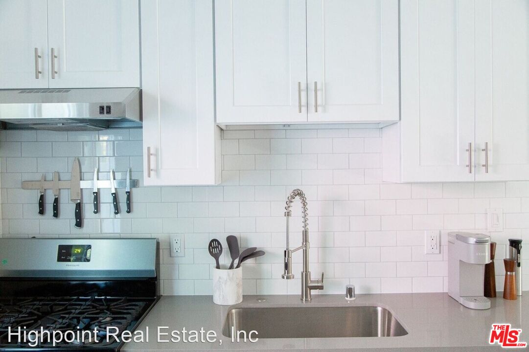 5525 Harold Way Los Angeles, CA 90028 - Photo 10 of 13 a kitchen with stainless steel appliances granite countertop a sink and white cabinets