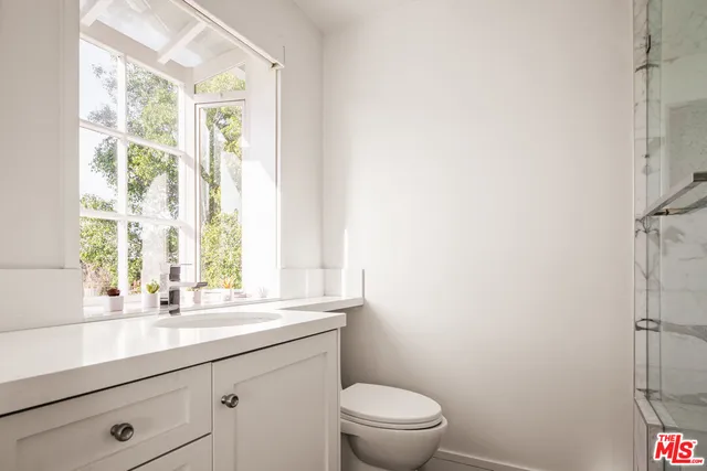 a bathroom with a granite countertop sink a toilet and a window