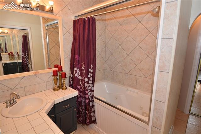 5720 Sayres Road Colorado Springs, CO 80927 - Photo 12 of 31 Master bathroom with beautiful tile floors, bath, counters and shower/tub with jacuzzi jets.