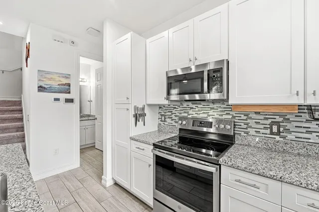 a kitchen with stainless steel appliances granite countertop a stove refrigerator and a sink