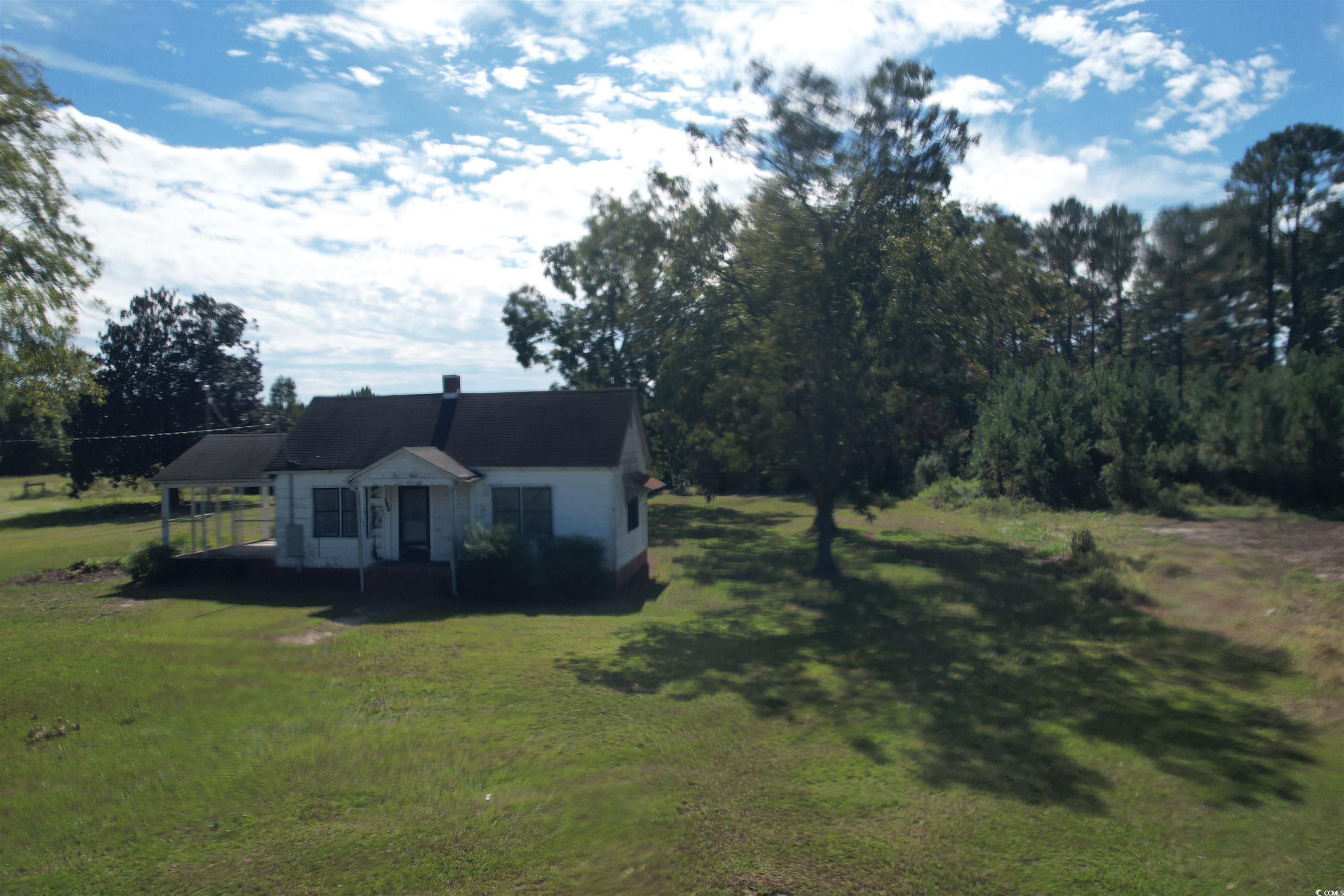 Bungalow-style home with a front lawn, an attached carport, and a chimney