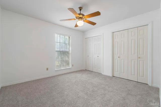 an empty room with closet and a chandelier fan