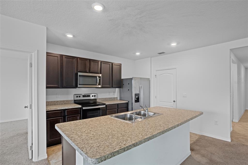 2143 Kalin Way Tavares, FL 32778 - Photo 20 of 37 a kitchen with kitchen island granite countertop a sink stove and refrigerator