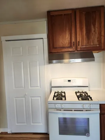 a stove top oven sitting inside of a kitchen with granite countertop wooden cabinets