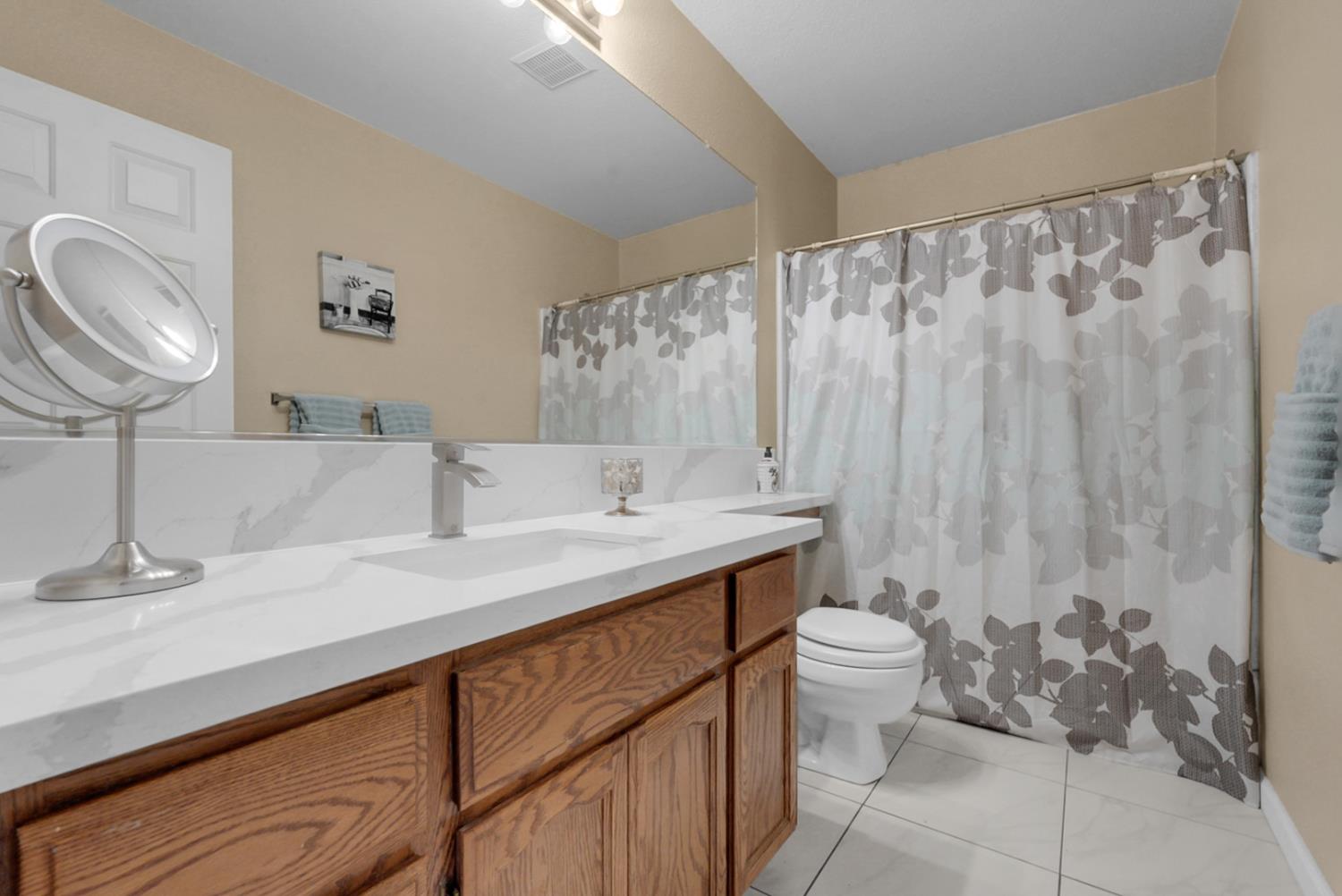 2809 Fleming Court Modesto, CA 95356 - Photo 17 of 34 a bathroom with a granite countertop sink a toilet and a mirror