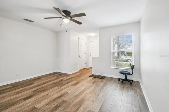 a view of empty room with wooden floor and fan