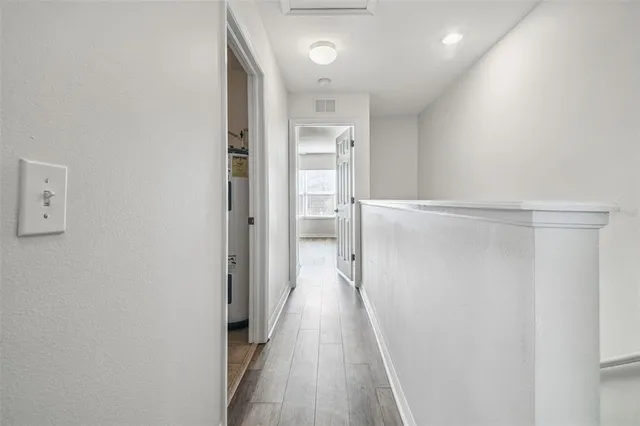 a view of a hallway with wooden floor and a bathroom
