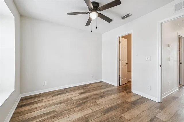 a view of a hallway with wooden floor and a bathroom