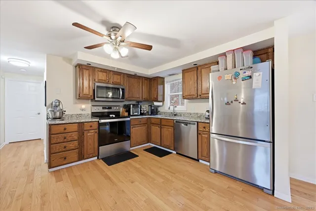 a kitchen with granite countertop stainless steel appliances a refrigerator stove top oven and cabinets