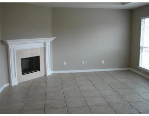 a view of an empty room with a fireplace and a window