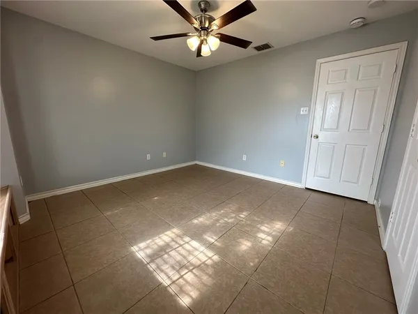 en empty room with windows and ceiling fan