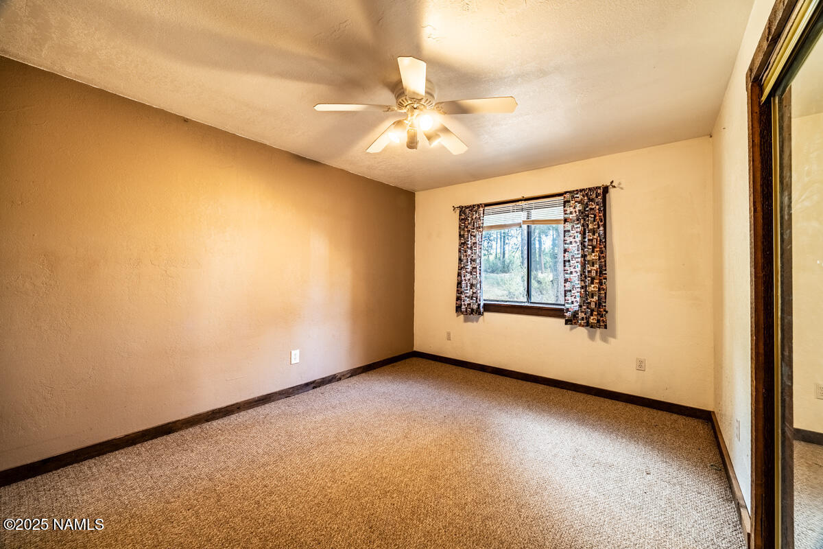 129 North Spitz Spring Road Parks, AZ 86018 - Photo 24 of 59 an empty room with a chandelier fan and windows
