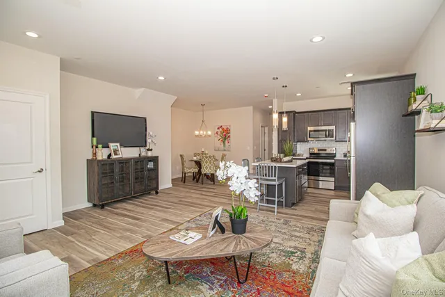a living room with furniture kitchen view and a wooden floor