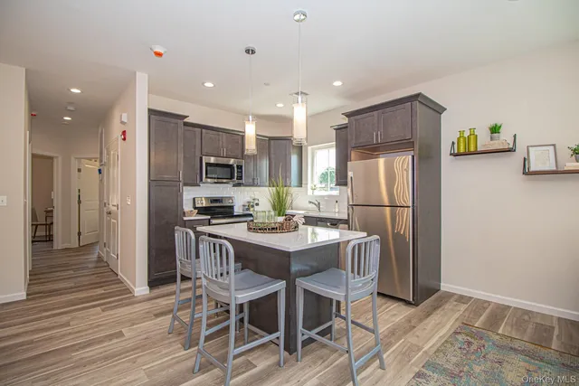 a kitchen with stainless steel appliances granite countertop a refrigerator a stove a sink dishwasher and a dining table with wooden floor