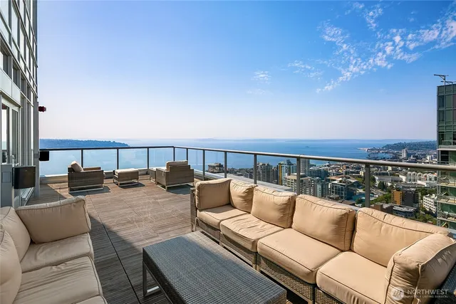a roof deck with couches and potted plants with sky view