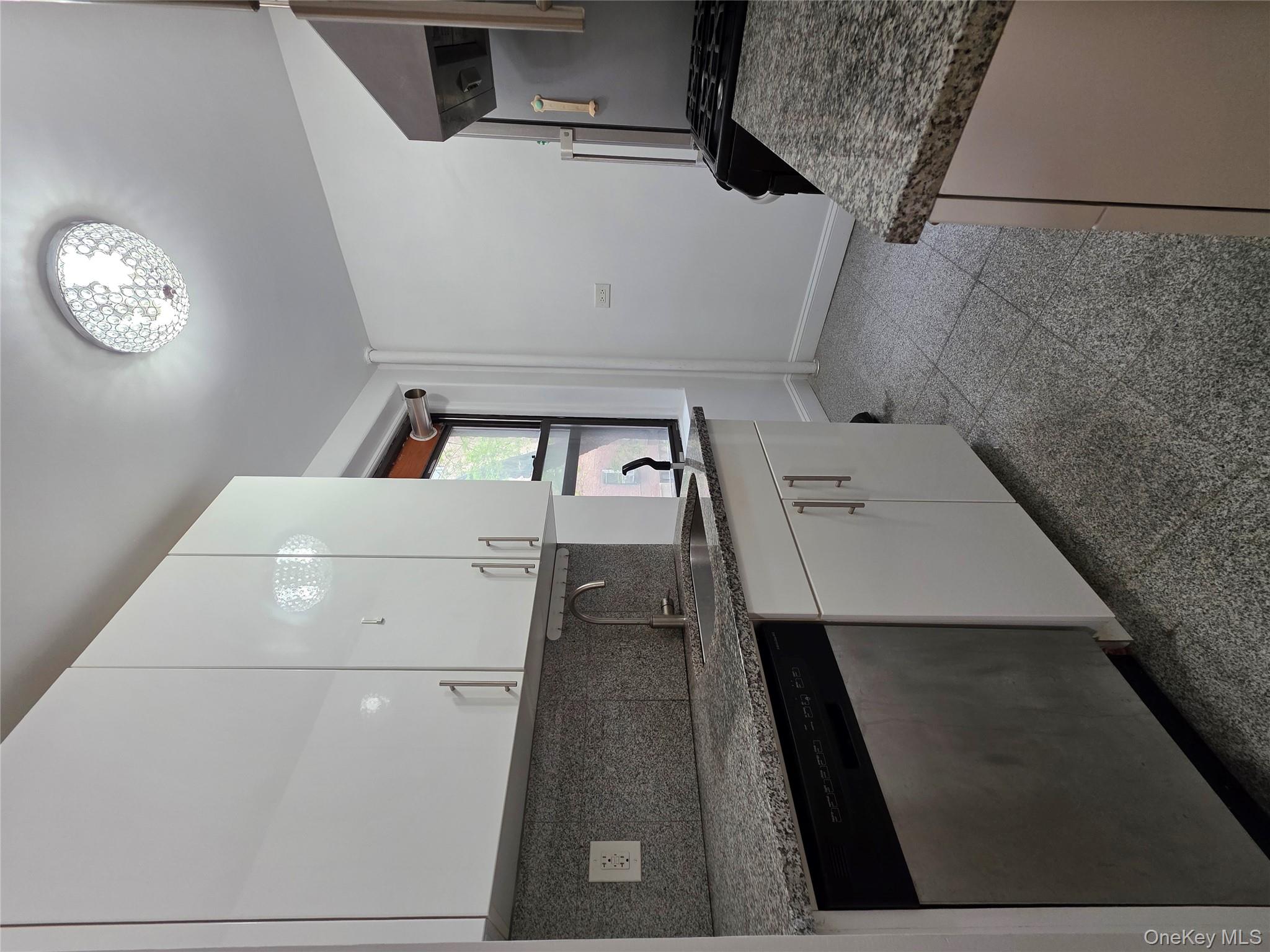 98-50 67th Avenue, Unit 1H Queens, NY 11374 - Photo 4 of 15 a kitchen with granite countertop a sink cabinets and stainless steel appliances