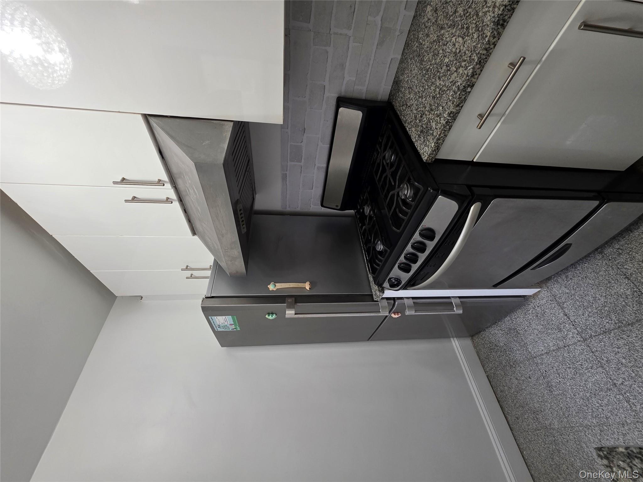 98-50 67th Avenue, Unit 1H Queens, NY 11374 - Photo 6 of 15 a kitchen with granite countertop a stove and a refrigerator