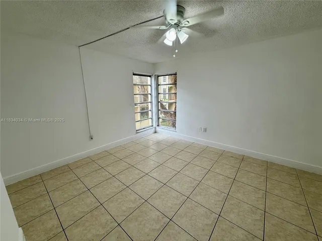 an empty room with windows and ceiling fan