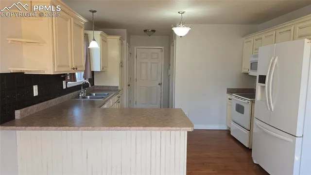 a kitchen with stainless steel appliances granite countertop a refrigerator a sink and white cabinets