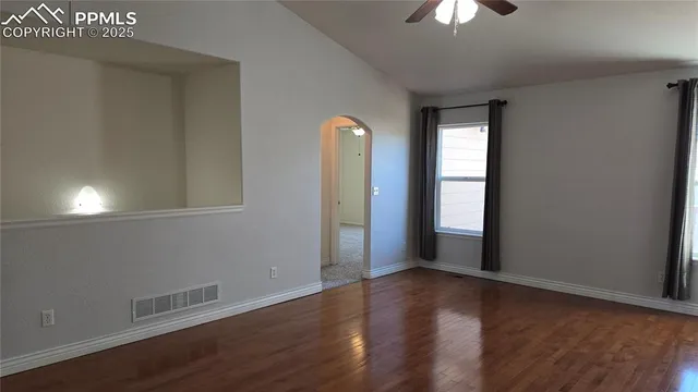 an empty room with wooden floor and windows