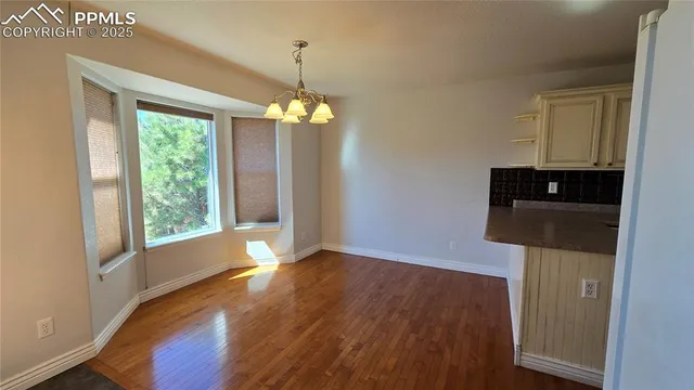 a view of a room with wooden floor chandeliers and kitchen view
