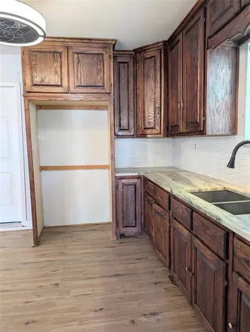 a kitchen with stainless steel appliances granite countertop a refrigerator a stove and a sink with wooden cabinets