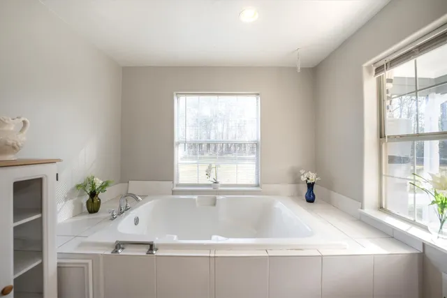 a spacious bathroom with a double vanity sink a large mirror and a bathtub