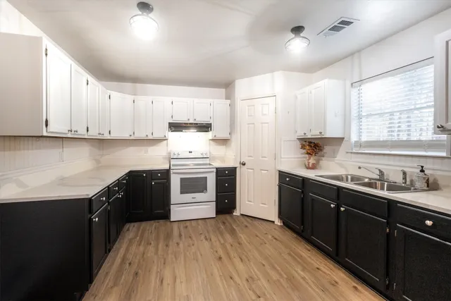 a kitchen with kitchen island granite countertop a sink cabinets and wooden floor