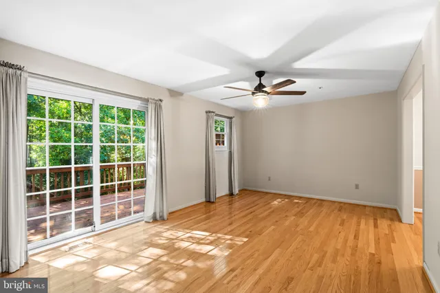 an empty room with windows and ceiling fan