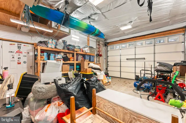 a view of a white house in front of a big yard with plants and large trees