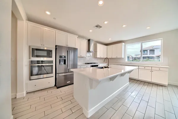 a large kitchen with stainless steel appliances double vanity and a refrigerator