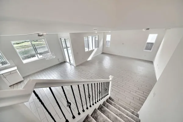 a view of an empty room with wooden floor and windows