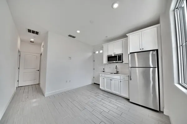 a kitchen with white cabinets white stainless steel appliances and wooden floor