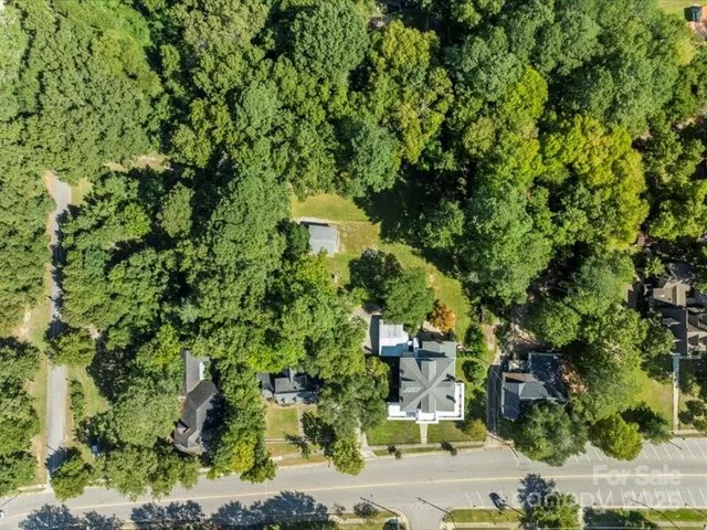an aerial view of residential houses with outdoor space and trees