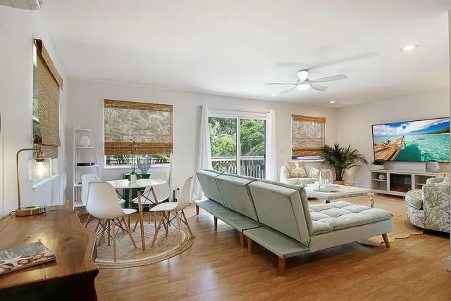 a living room with furniture kitchen view and a wooden floor