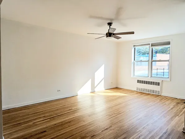 a view of an empty room with a window and wooden floor