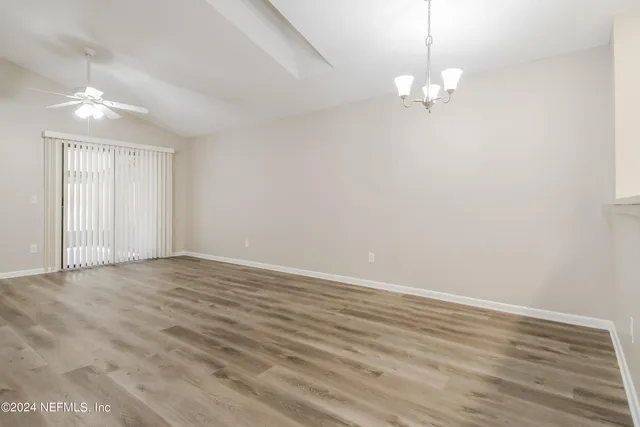 a view of an empty room with wooden floor and chandelier