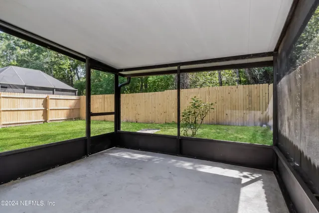 an empty room with large windows and yard