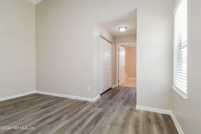 a view of an empty room with wooden floor and a window