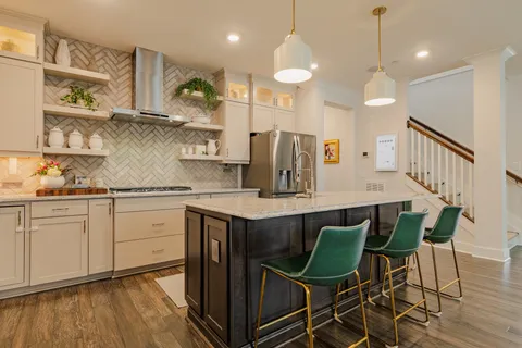 a kitchen with stainless steel appliances granite countertop a sink a stove a refrigerator and wooden floor