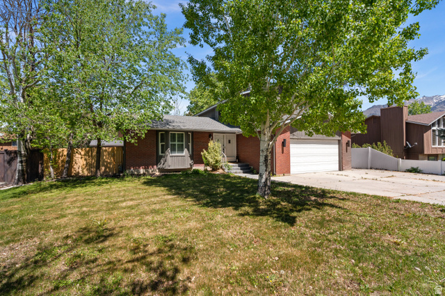View of front of property featuring brick siding, concrete driveway, a porch, and a garage