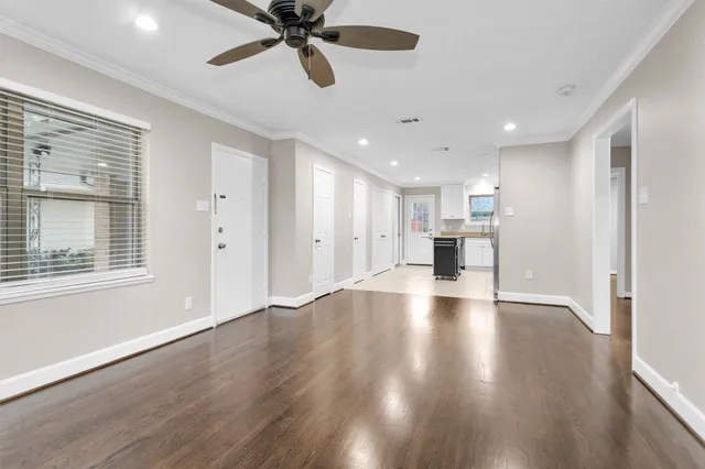 a view of an empty room with a window and wooden floor