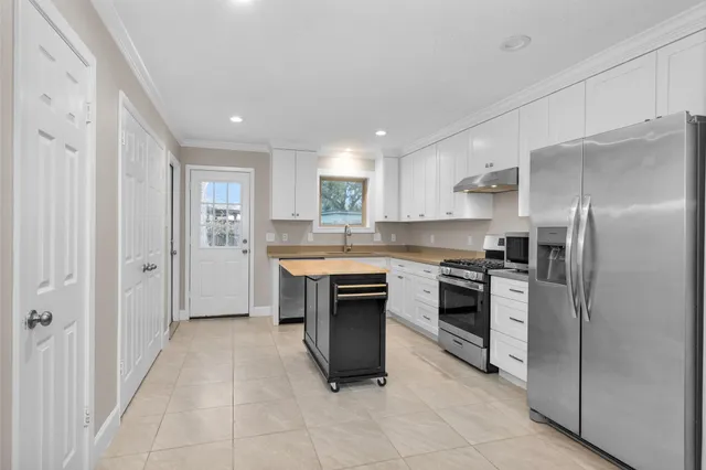 a kitchen with stainless steel appliances granite countertop a refrigerator stove top oven and sink
