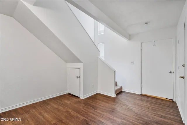 a view of an empty room with wooden floor and stairs