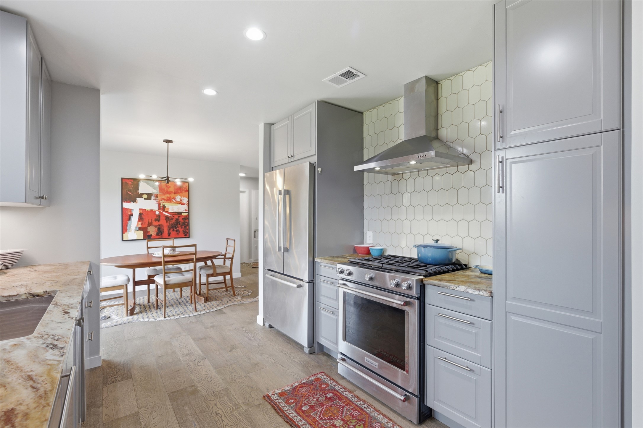 3208 Yellowpine Terrace Austin, TX 78757 - Photo 5 of 35 a kitchen with stainless steel appliances granite countertop a stove a refrigerator and a dining table with wooden floor