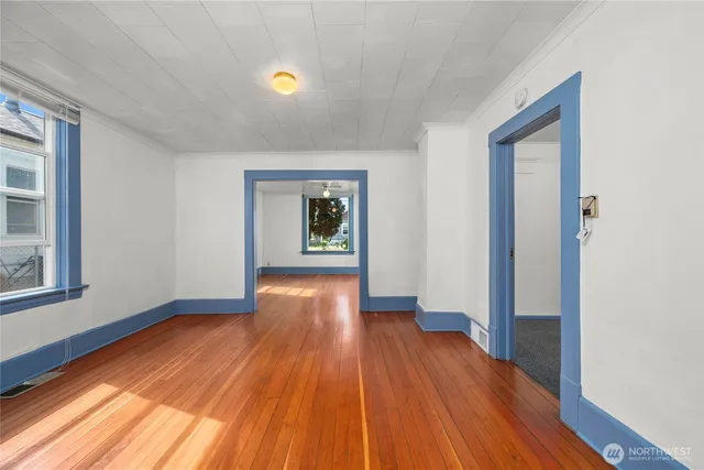a view of an empty room with wooden floor and a window