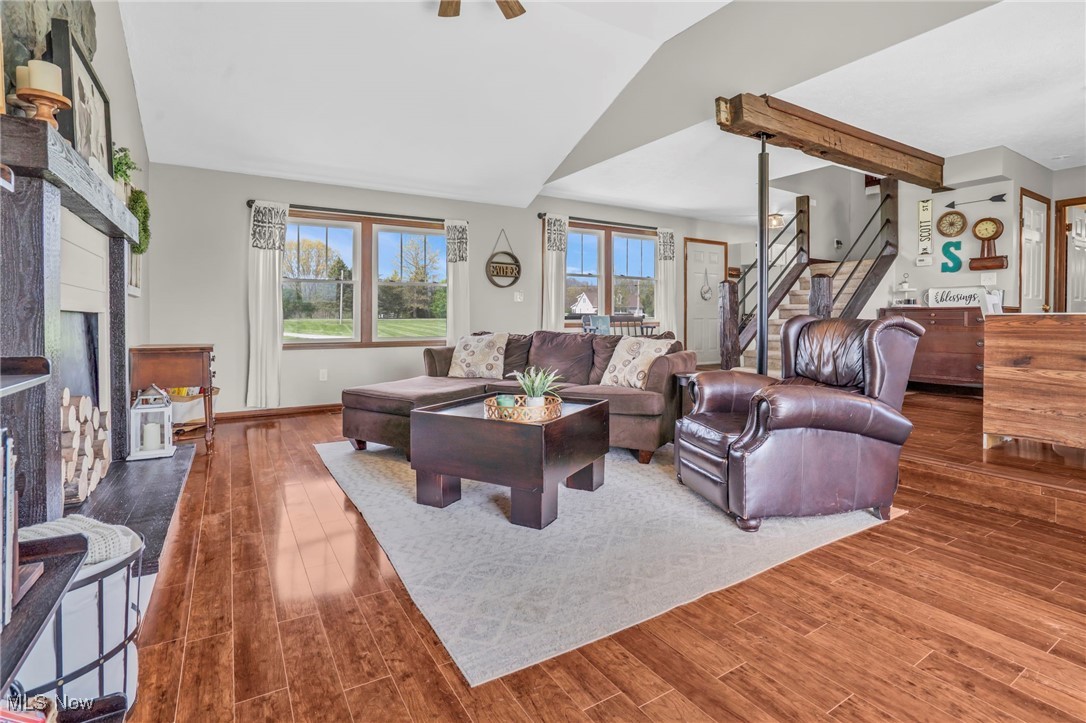 39233 Jones Road Litchfield, OH 44253 - Photo 11 of 46 Living room featuring baseboards, vaulted ceiling, a fireplace, wood finished floors, and stairs